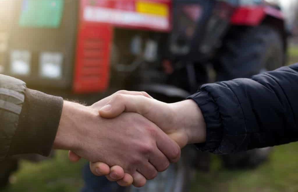 Pessoas apertando as mãos, sinalizando fechamento de negócio na comercialização de máquinas agrícolas