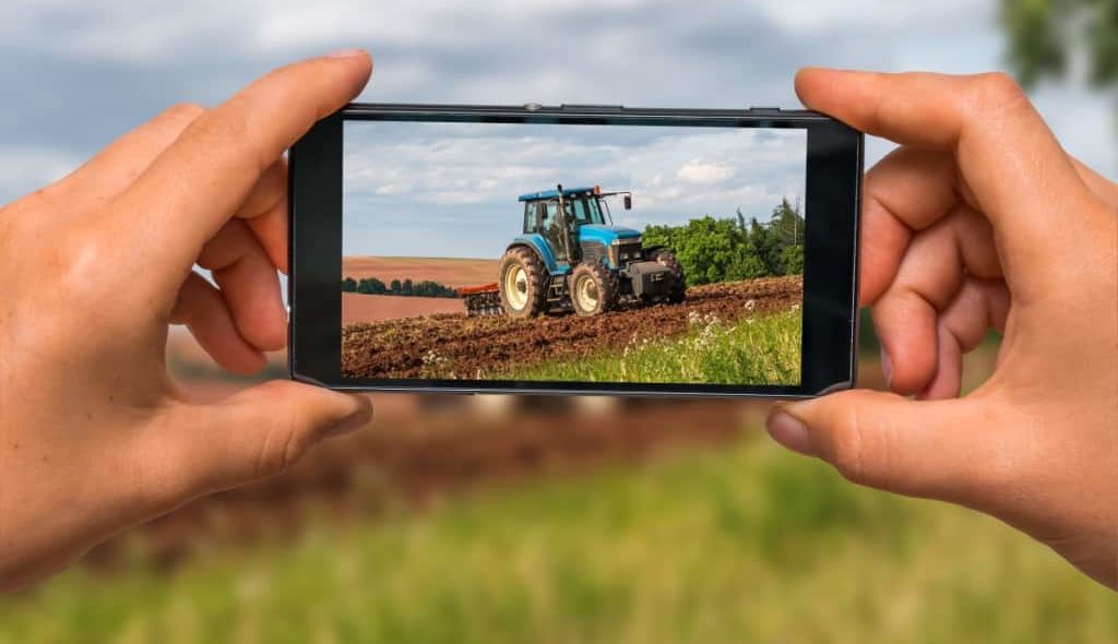 Agricultor tirando foto pelo celular de um trator para vender