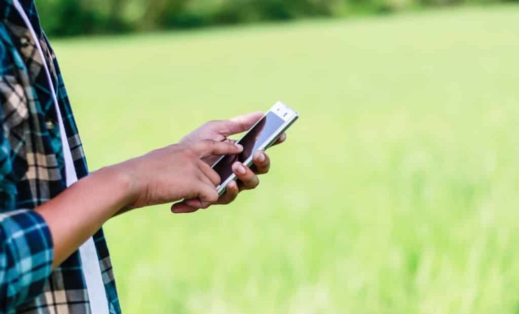 homem com celular no campo