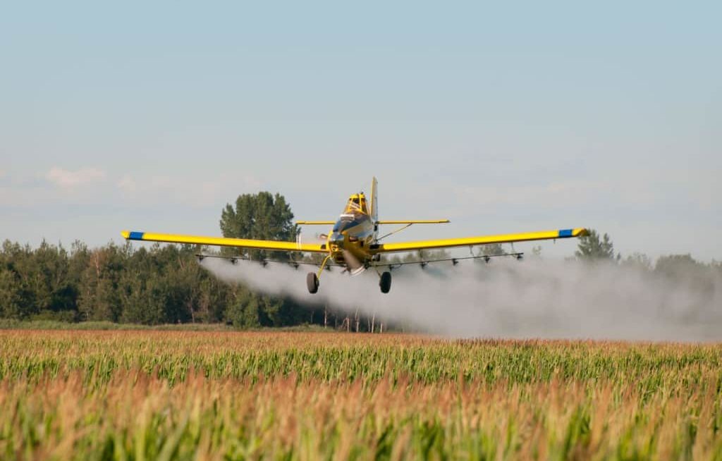 Avião aplicando defensivo na lavoura