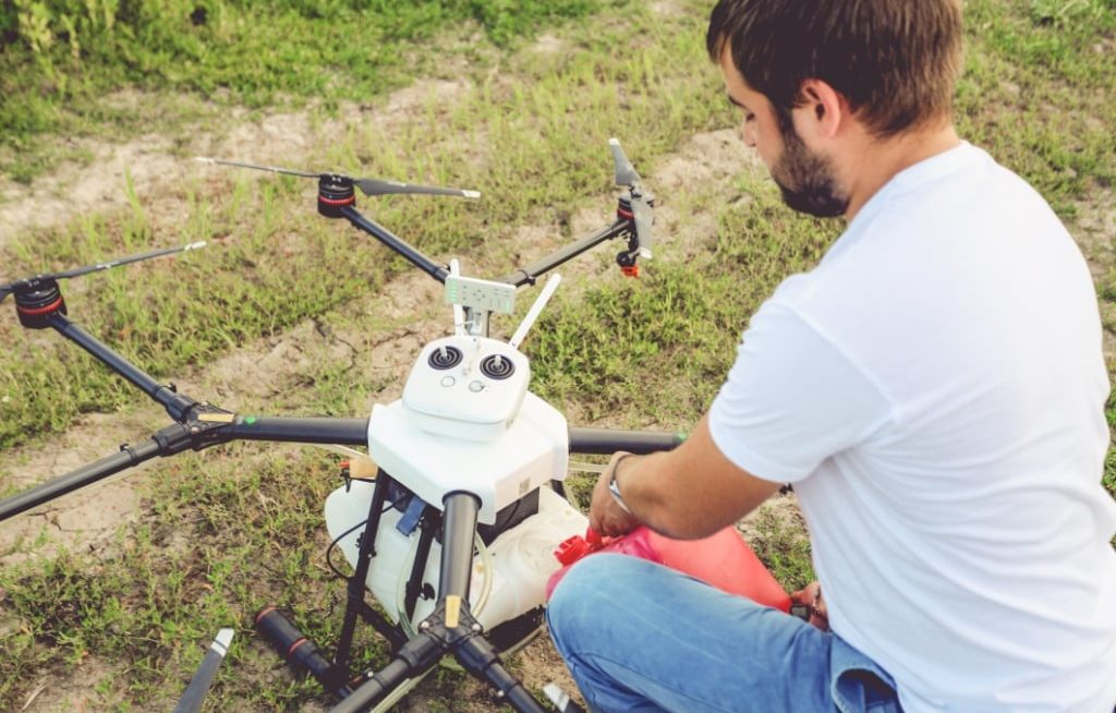 Homem abastecendo drone no chão
