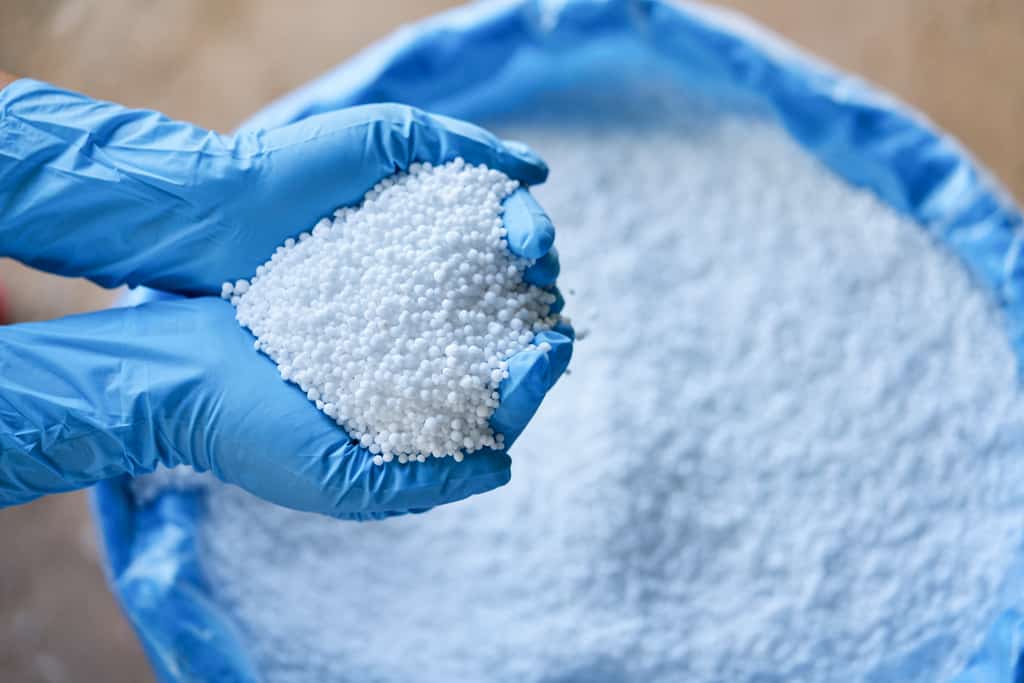 Mão com luvas cheia de fertilizante