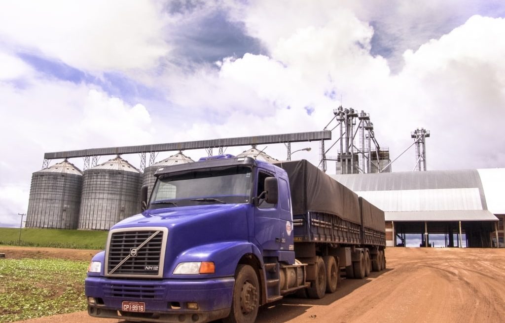 Caminhão graneleiro em frente um silo