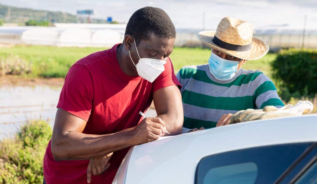 Dois homens assinando contrato numa área agrícola
