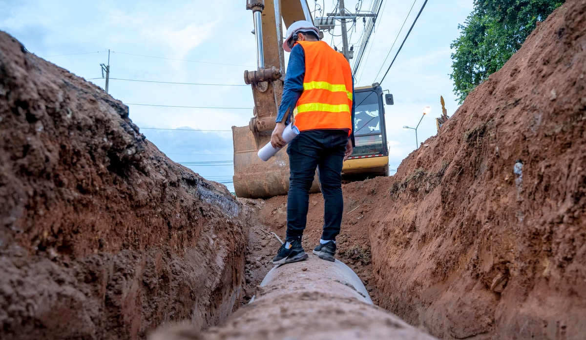 Engenheiro examinando a tubulação de drenagem de concreto da escavação