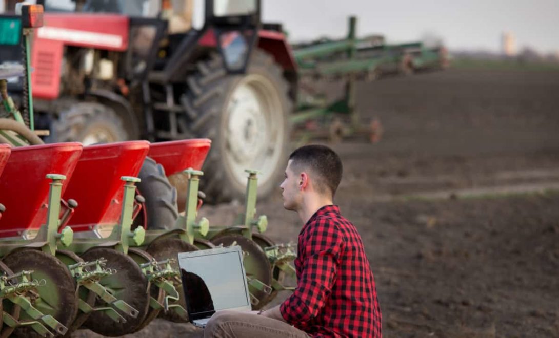 Agricultor com notebook analisa dados das produção agrícola