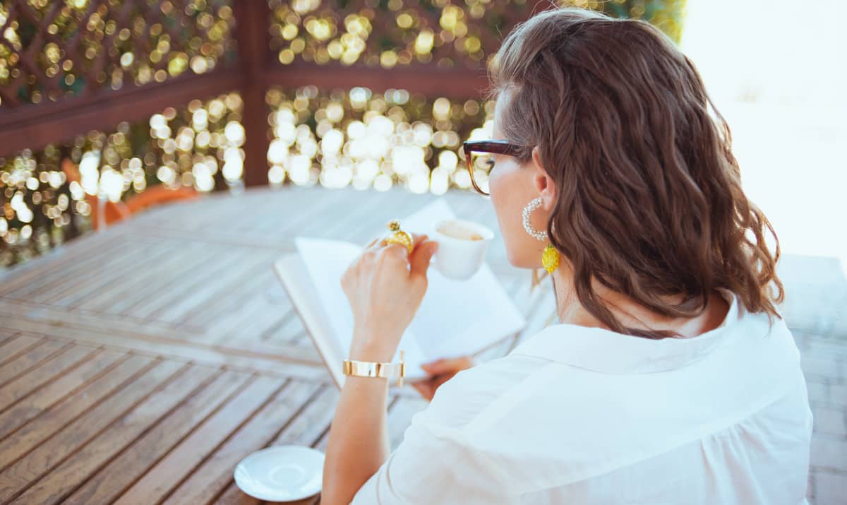 Mulher lendo um livro e tomando café. Benefícios da bebida