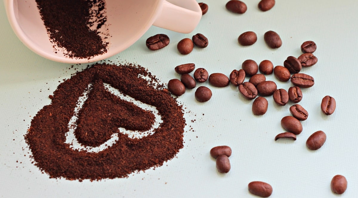 Café em grãos e moído, em forma de coração, indicando benefícios à saúde