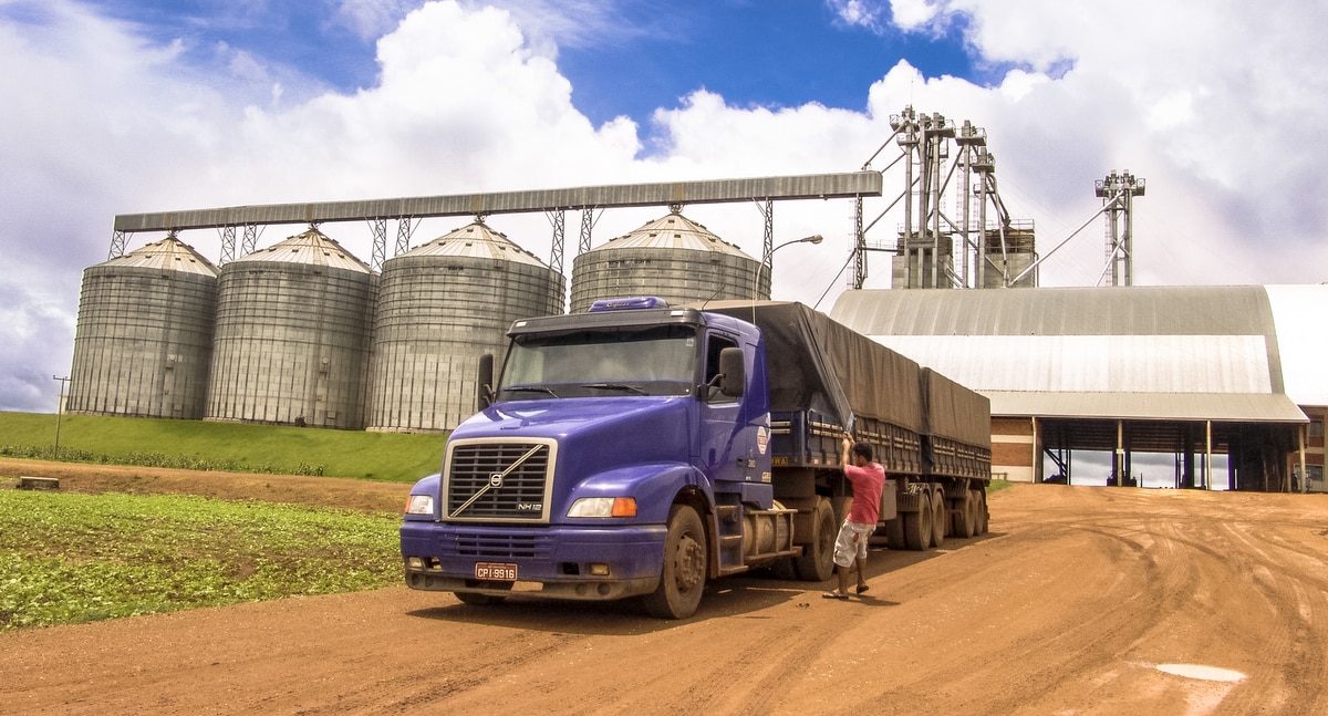 Carreta na frente de silo de grãos. Estratégia para baratear custo com o frete
