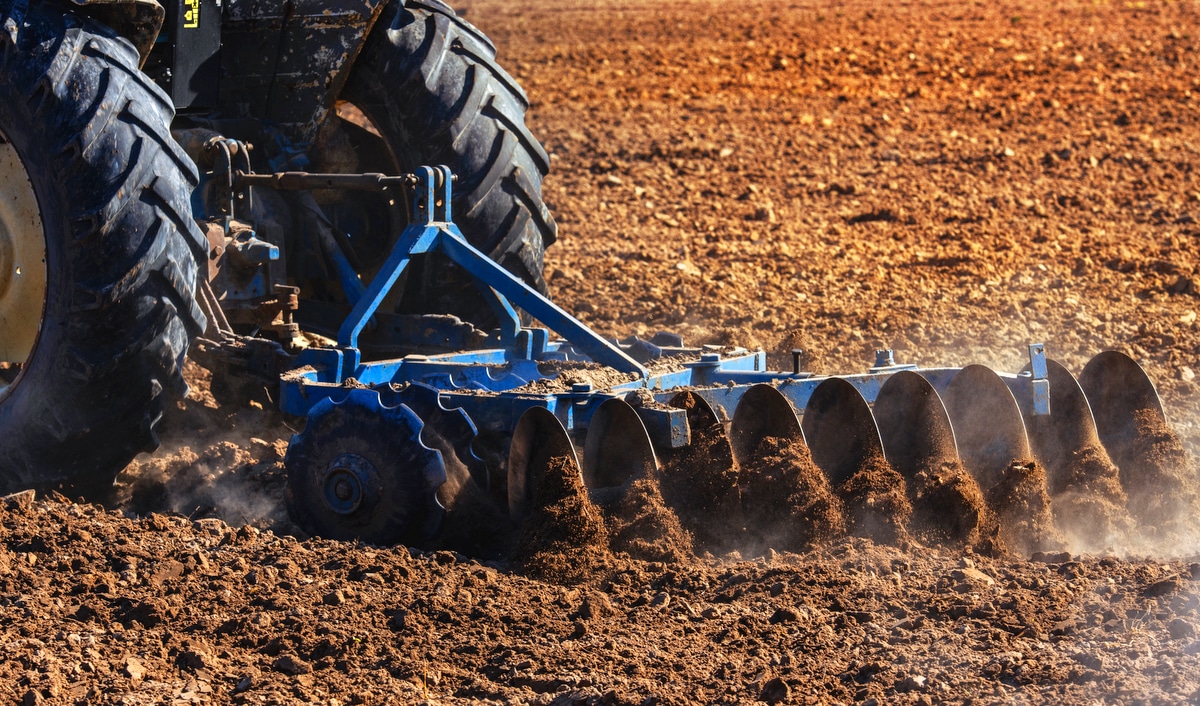 Implemento agrícola, puxado por trator, preparando o solo