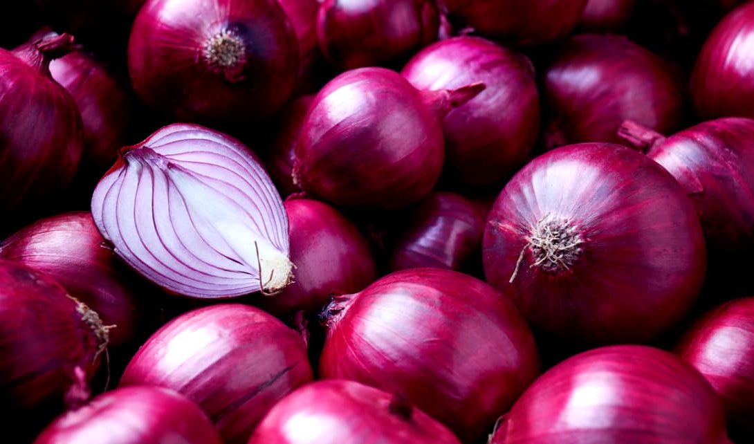 Cebolas roxas inteiras e uma cebola roxa cortada ao meio