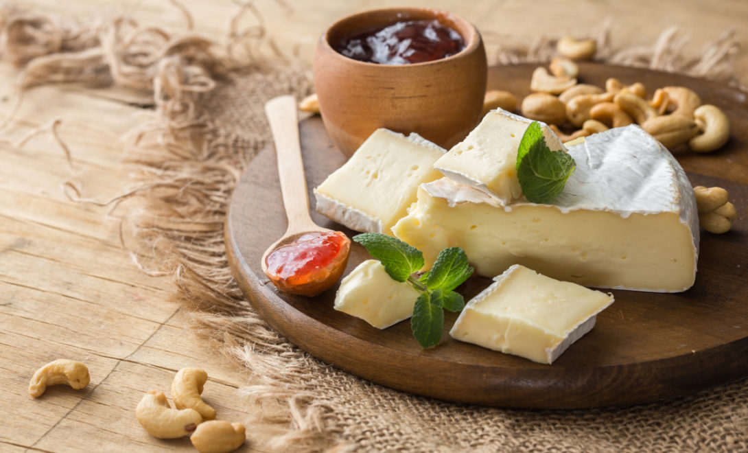 Queijo brie em tábua de madeira acompanhado de geléias e castanhas