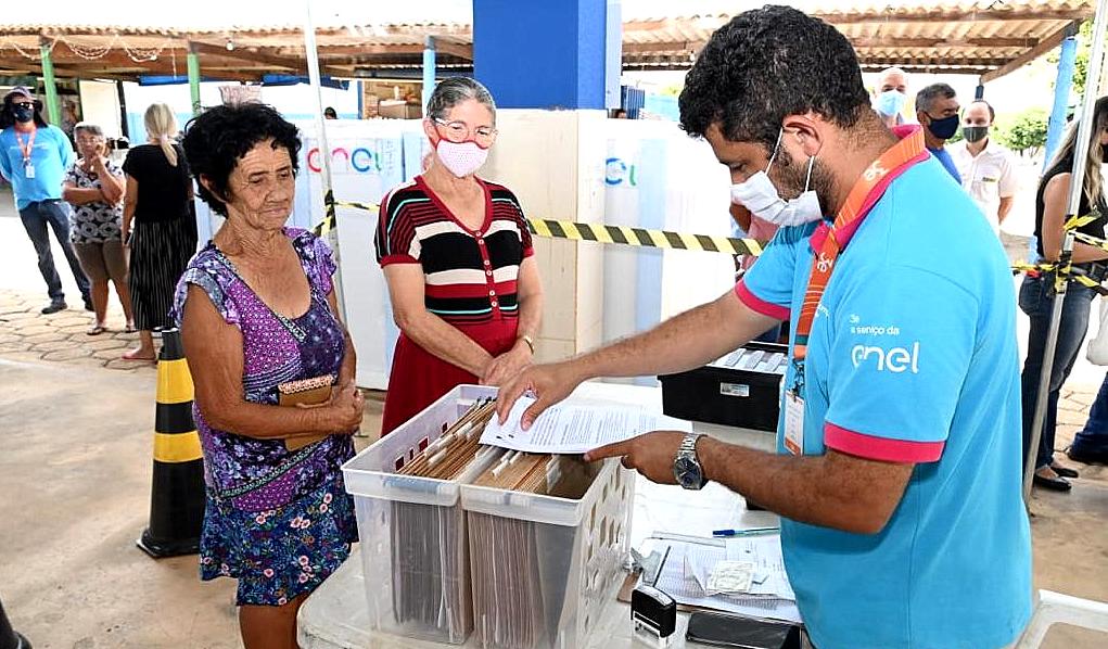Atendimento de clientes por funcionário da ENEL durante caravana