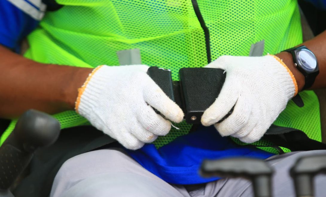 Trabalhador apertando os cintos em máquina agrícola