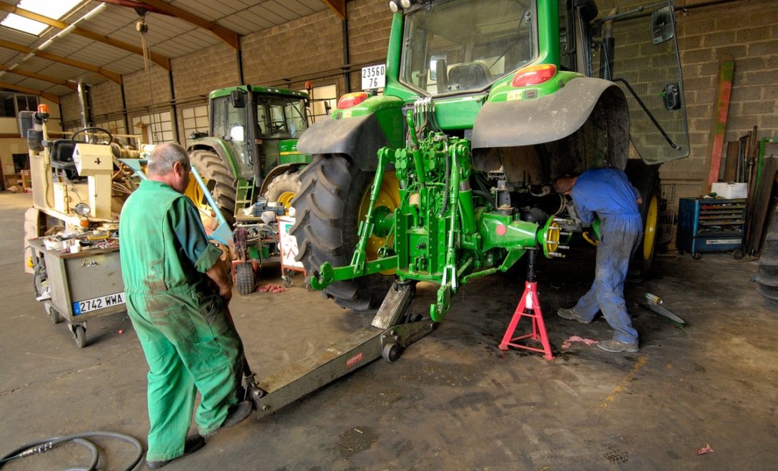 Trabalhadores realizando manutenção de trator agrícola