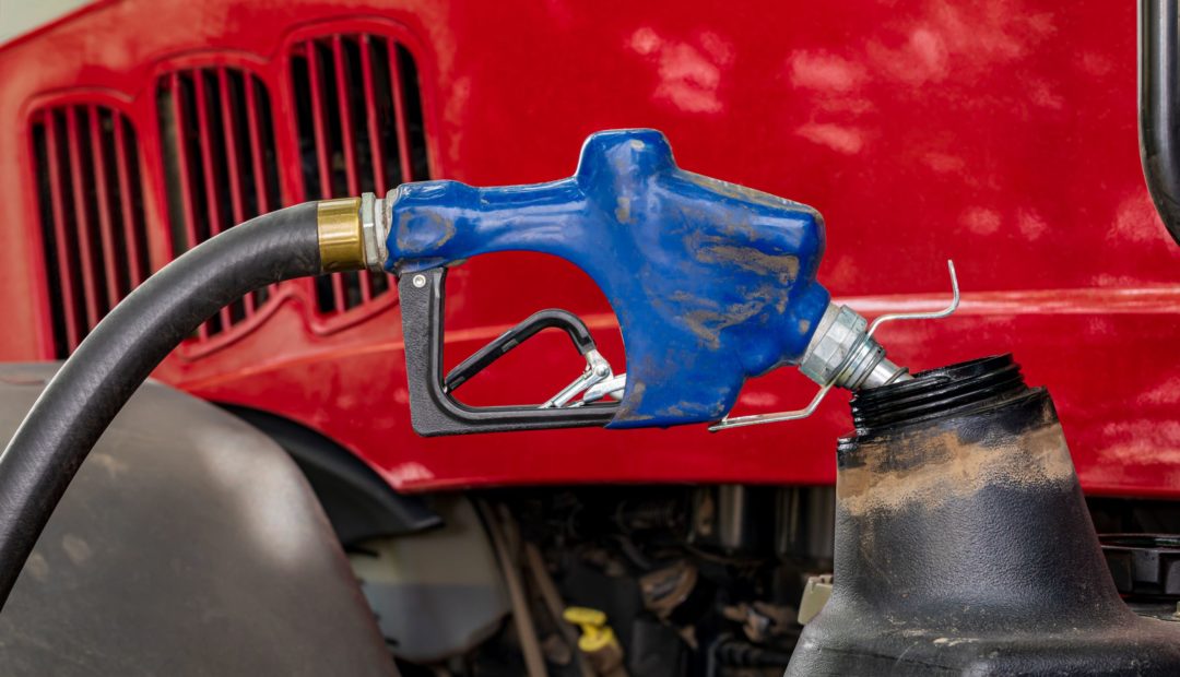 Trator sendo abastecido com óleo diesel por meio de bomba de combustível na cor azul.
