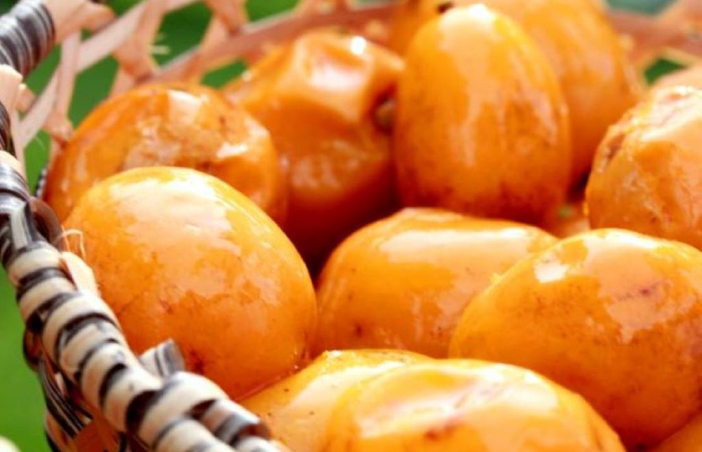 Frutos de cajá maduros de cor alaranjada em uma cesta de palha