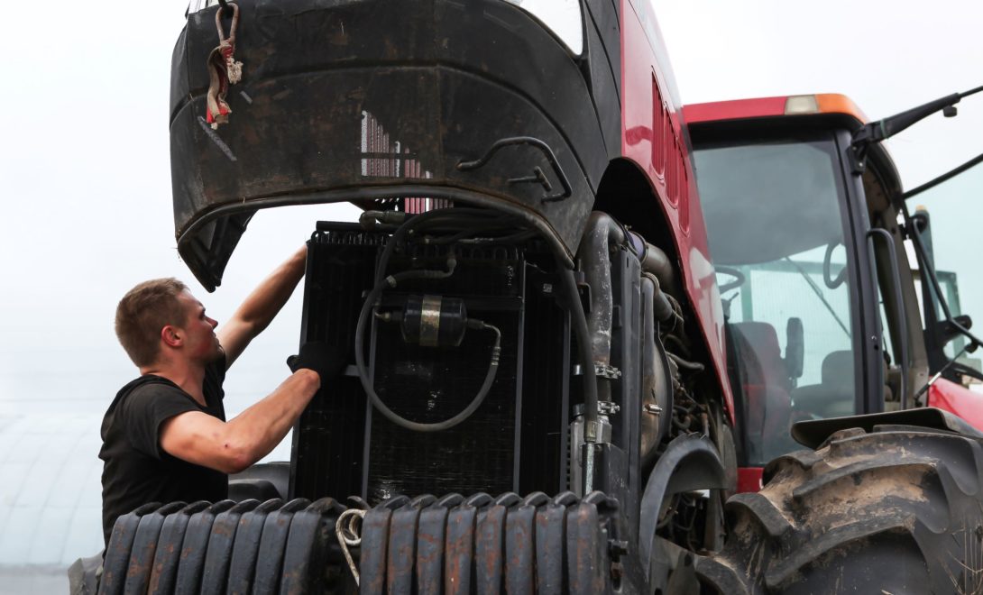 Homem realizando manutenção em trator