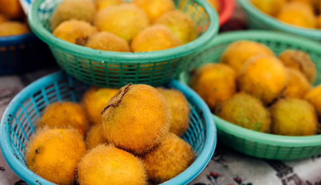 Cestas de plástico coloridas com frutos de cor amarela e pelos em sua casca