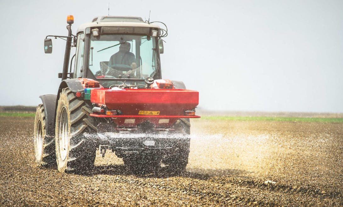 Trator com distribuidor de fertilizantes em operação