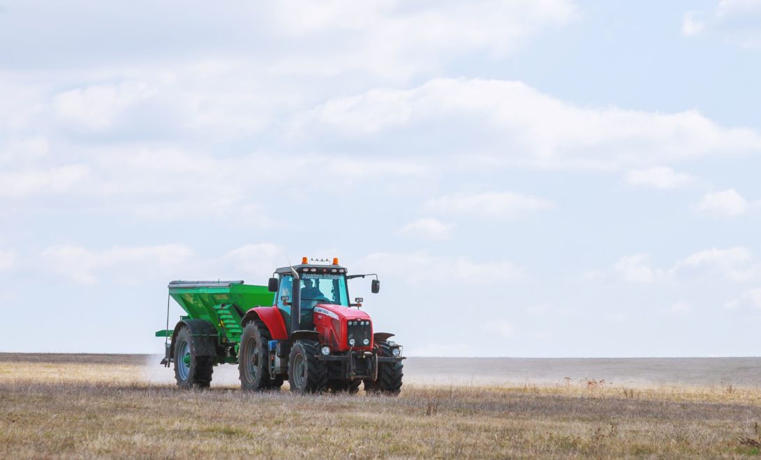 Trator com distribuidor de fertilizantes acoplado em operação