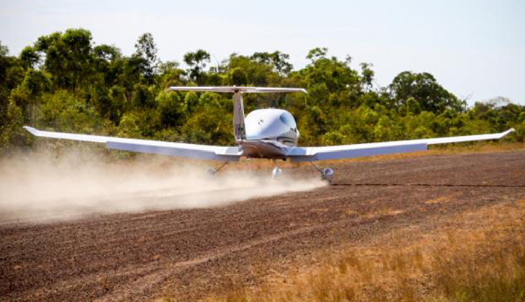 Avião pousando em pista exposta sem revestimento (ou exposta) em área rural