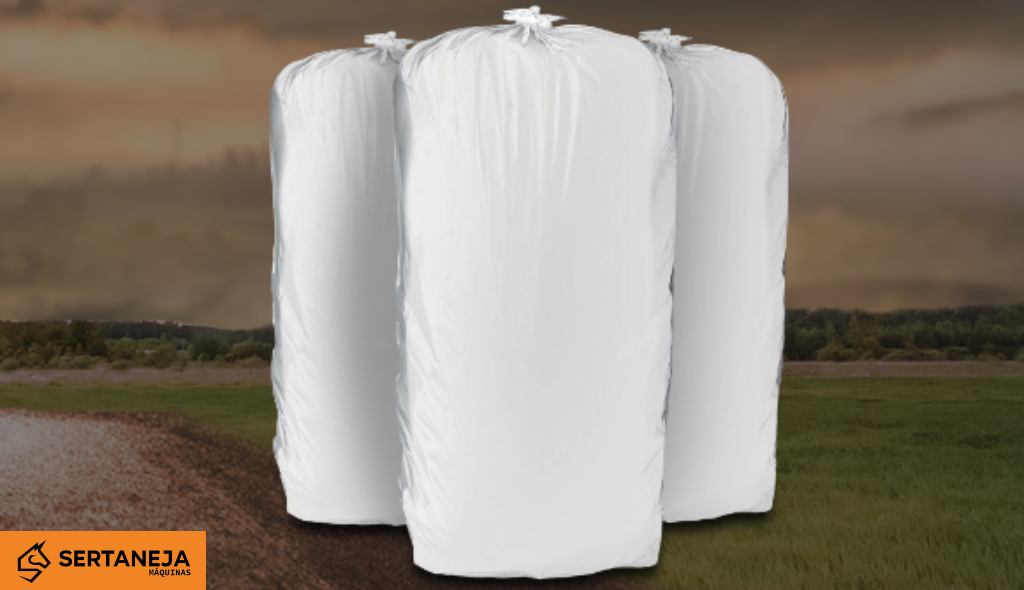 Três sacos para armazenamento de silagem em destaque. Ao fundo, paisagem campestre