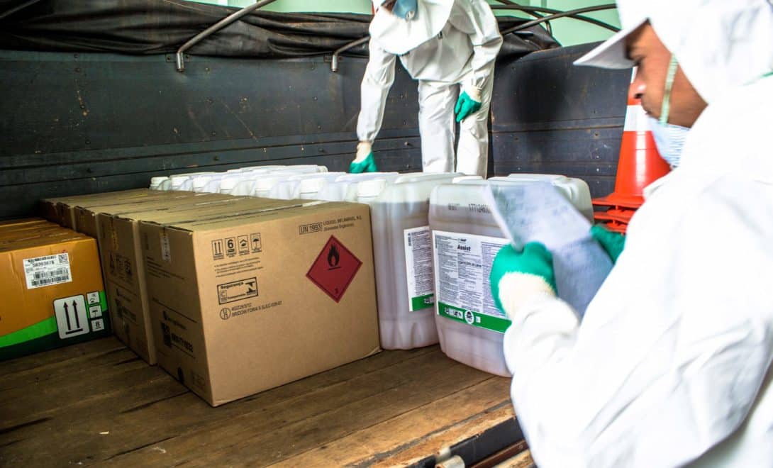 Homens utilizando EPI organizando embalagens de produtos fitossanitários em carroceria de caminhão