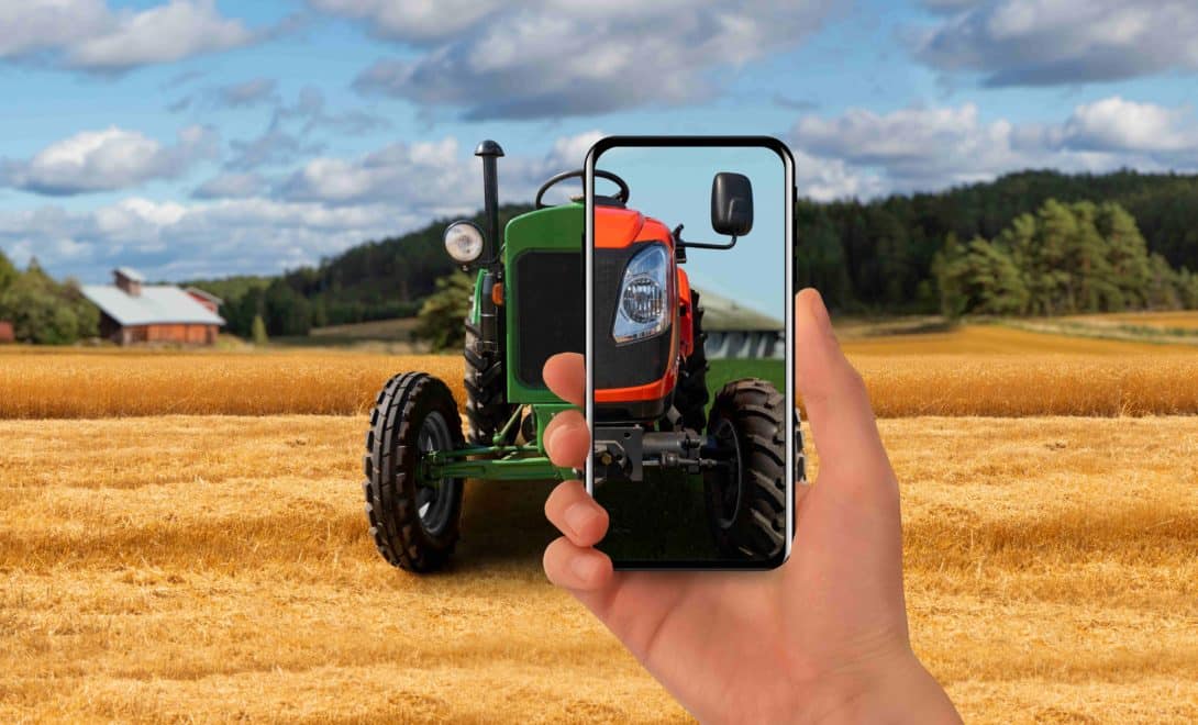 Trator antigo em campo de trigo e homem segurando celular com imagem de trator mais moderno