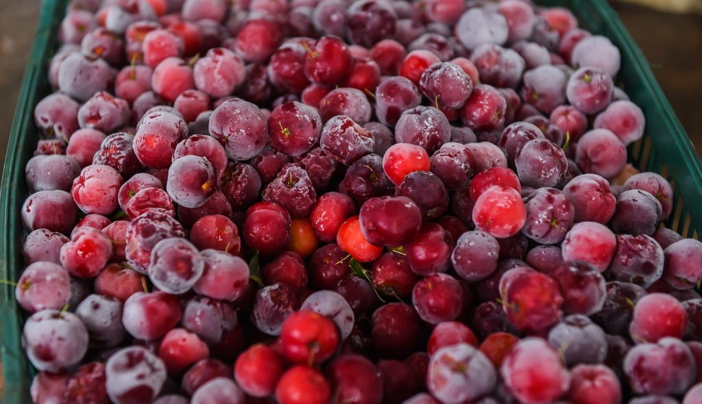 Frutos de acerola contidos em caixa, com destaque para a sua coloração avermelhada e viva