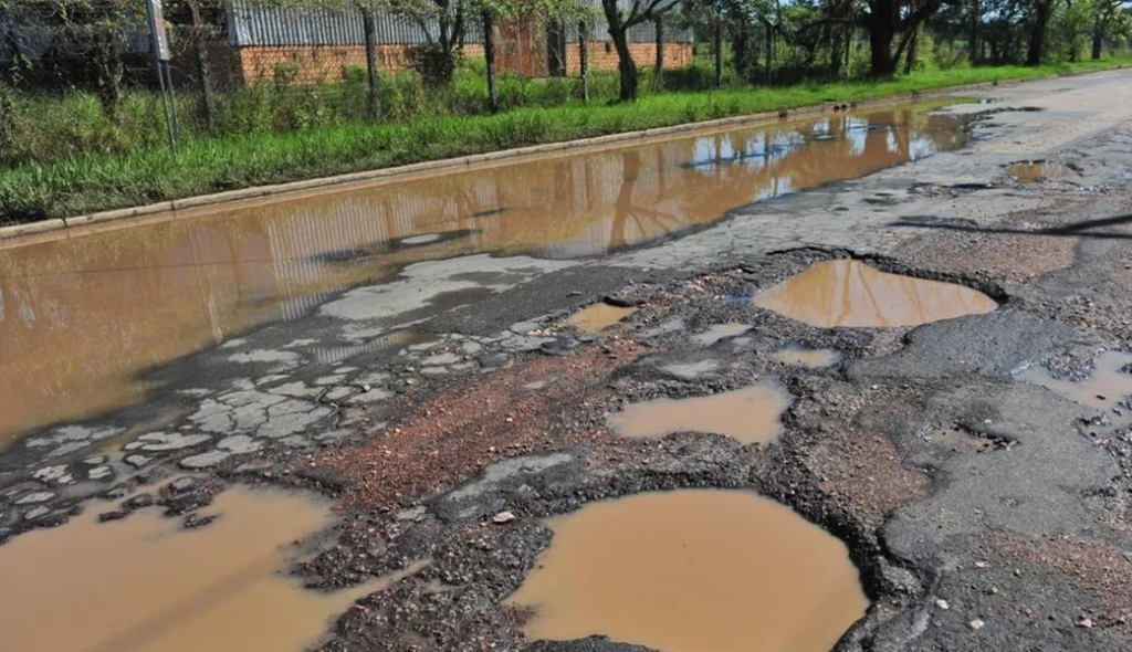 Estrada com inundação e buracos no asfalto