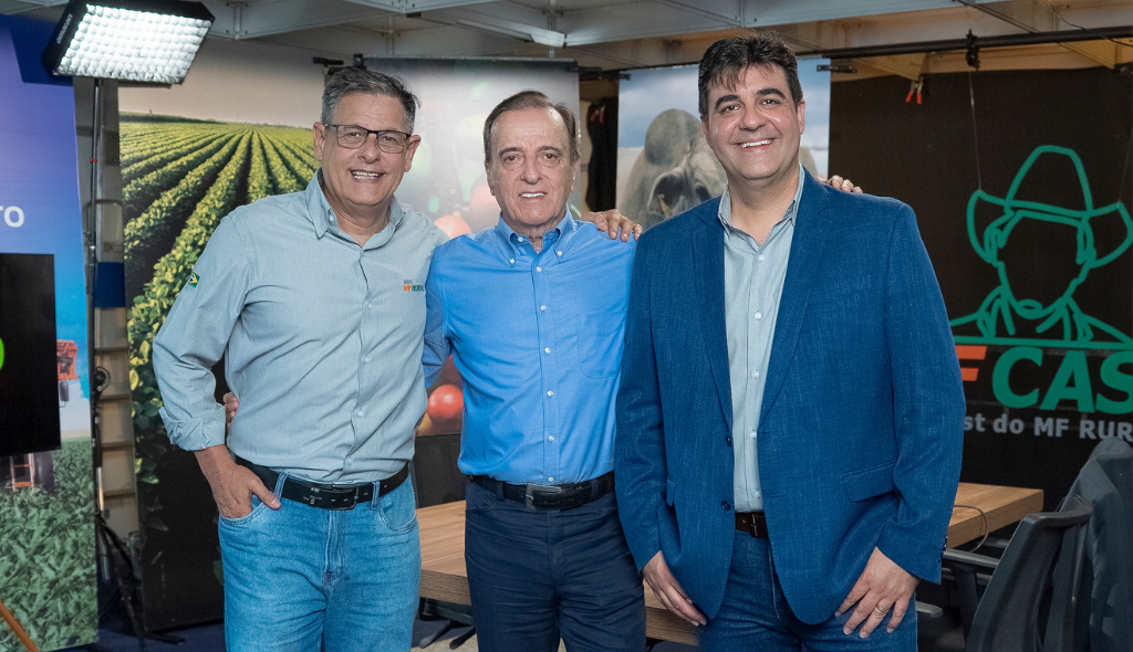 Walter Celani, Henrique Prata e Roberto Lucas Três homens estão lado a lado em um estúdio, sorrindo e com os braços apoiados uns nos outros em clima de amizade. Eles vestem camisas sociais, sendo um deles com blazer azul. Ao fundo aparecem painéis com imagens do agronegócio e a identidade visual do MF Cast, incluindo o desenho de um chapéu e o nome do programa. Há também iluminação de estúdio e uma mesa de gravação, indicando um ambiente de podcast ou entrevista.